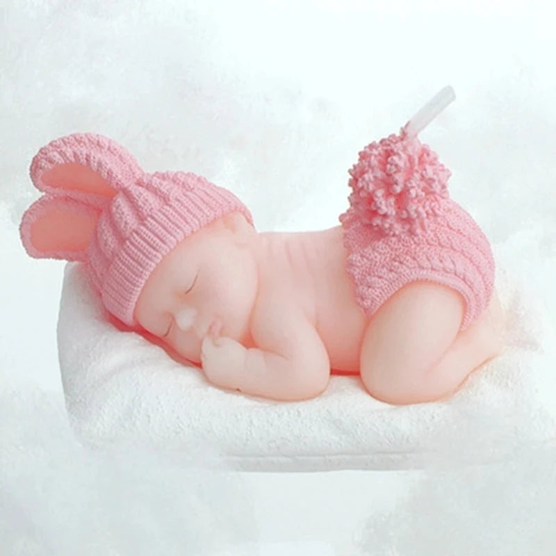 Schlafende Baby-Kerze in Rosa mit gestrickter Hasenmütze und passender Hose, auf einem weißen Kissen liegend.