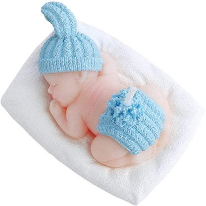 Blaue Baby-Kerze in Form eines schlafenden Babys mit gestrickter Hasenmütze und Bommel-Hose, auf Kissen liegend.